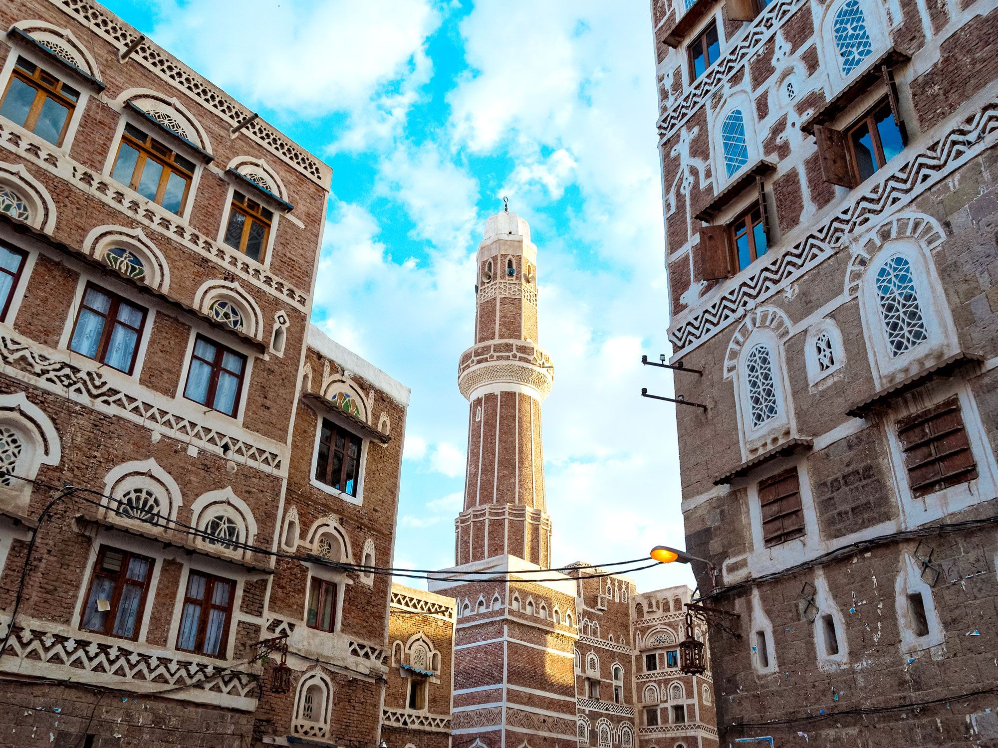 View of mosque framed by red-brick buildings in Sana'a, Yemen