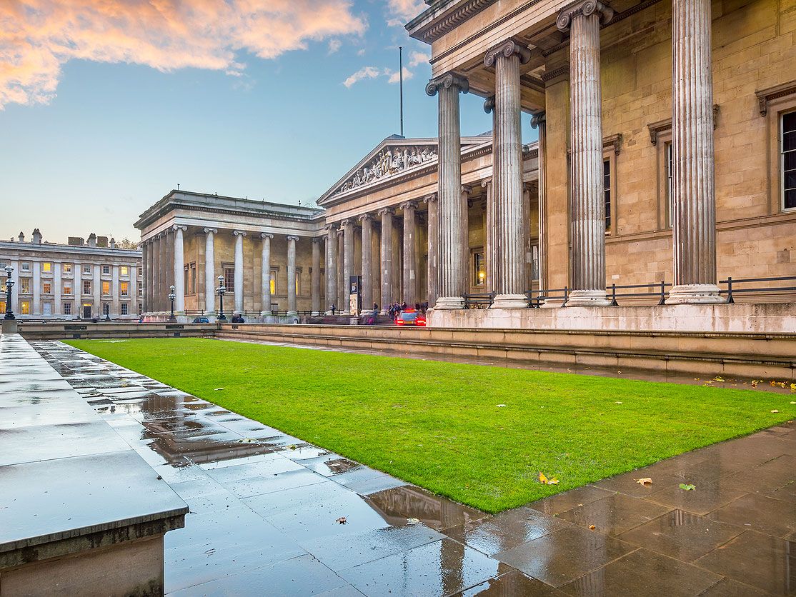 Classical columned exterior of British Museum with grassy lawn in front
