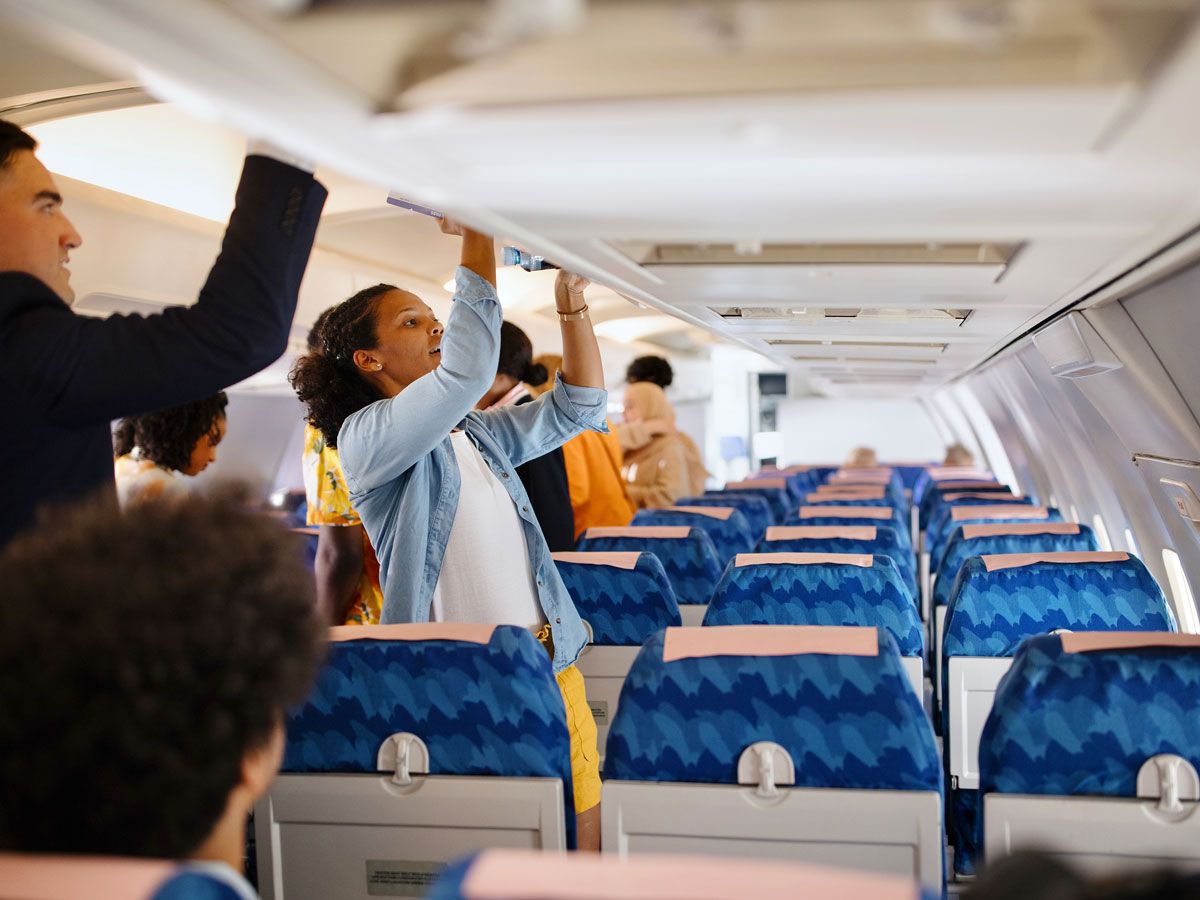 Passengers stowing carry-on luggage on airplane