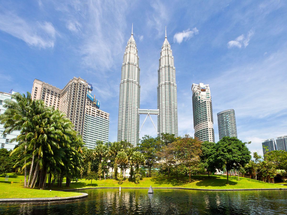 Connected twin Petronas Towers with park and lake in foreground in Kuala Lumpur, Malaysia