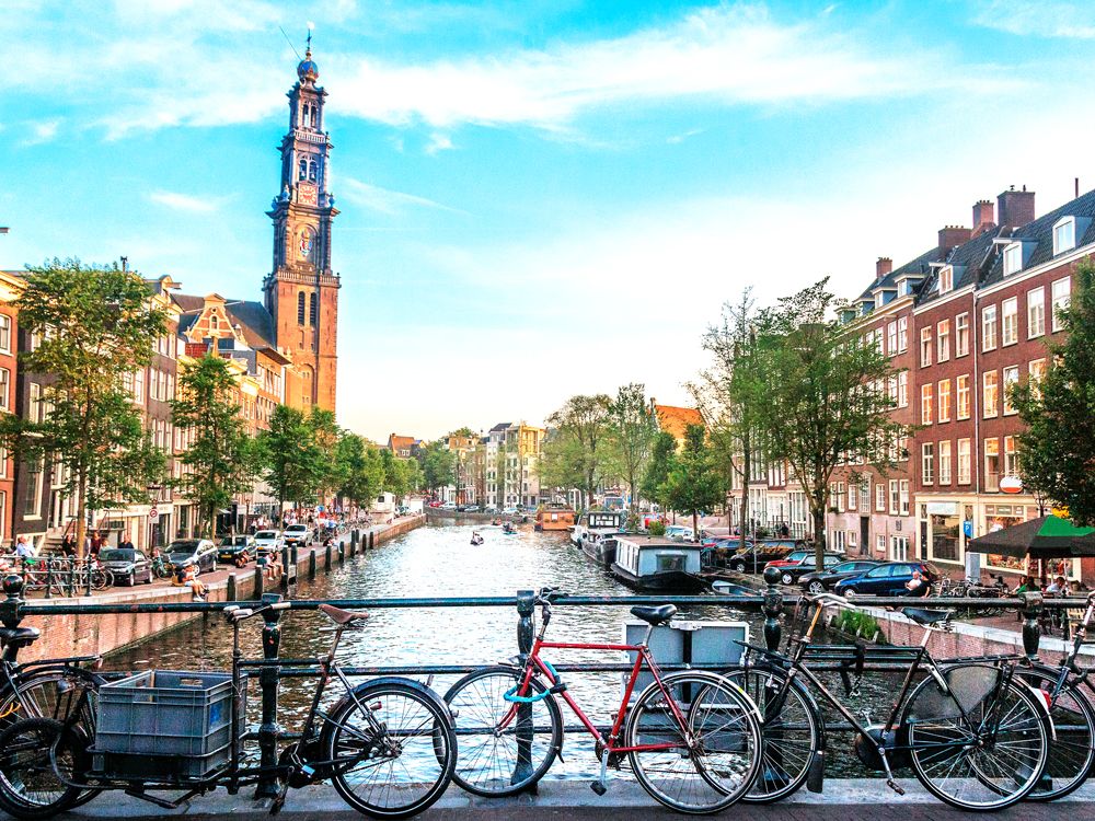 Bicycles parked on bridge over canal in Amsterdam, Netherlands