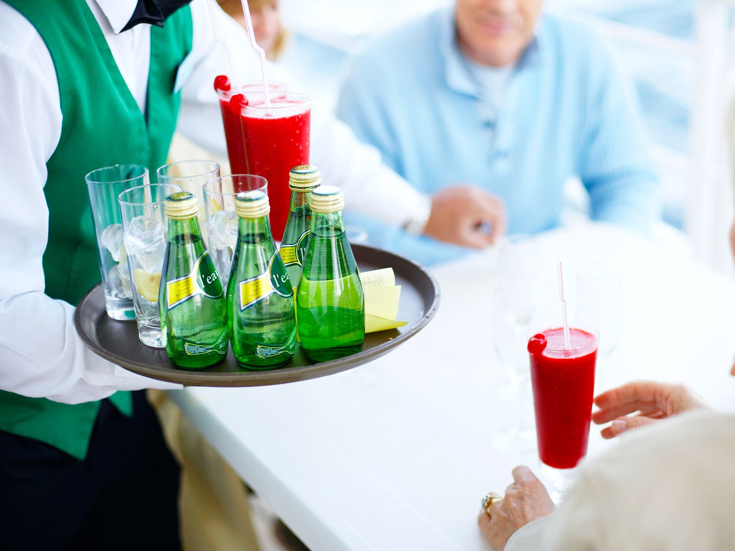 Cruise ship waiter with tray of drinks at table