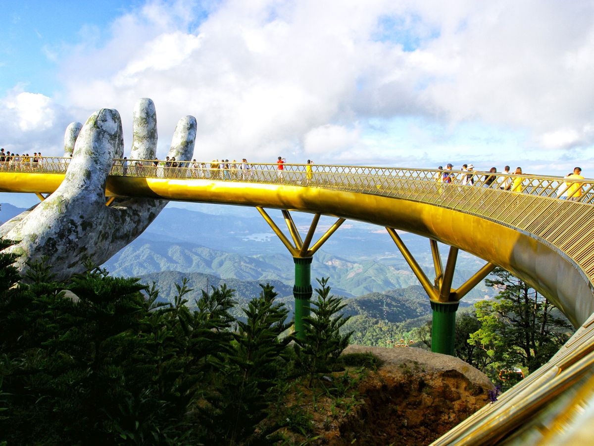 Tourists walking on Golden Bridge, held up by a statue of a human hand, in Vietnam