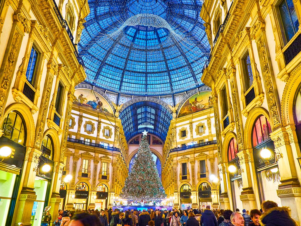 Shoppers and towering Christmas tree inside Milan's Galleria Vittorio Emanuele II shopping arcade