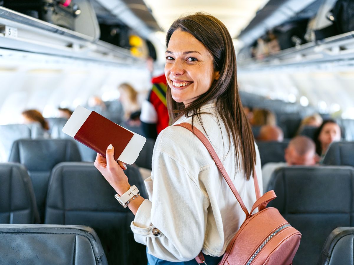 Passenger in airplane aisle looking back toward camera