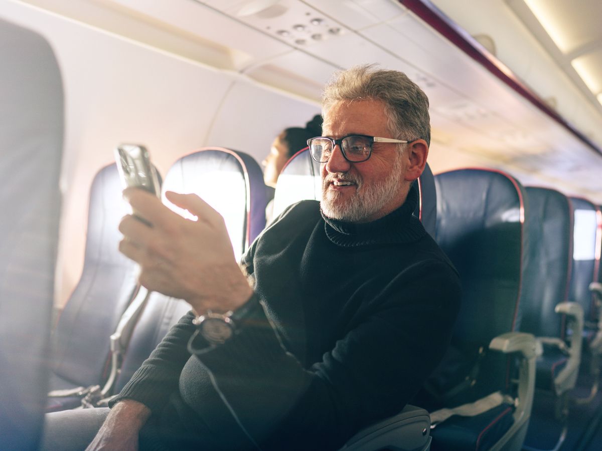 Passenger sitting in airplane seat using cellphone