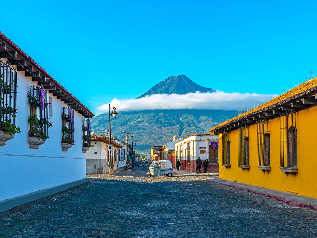 Car driving on street in Guatemala with view of volcano
