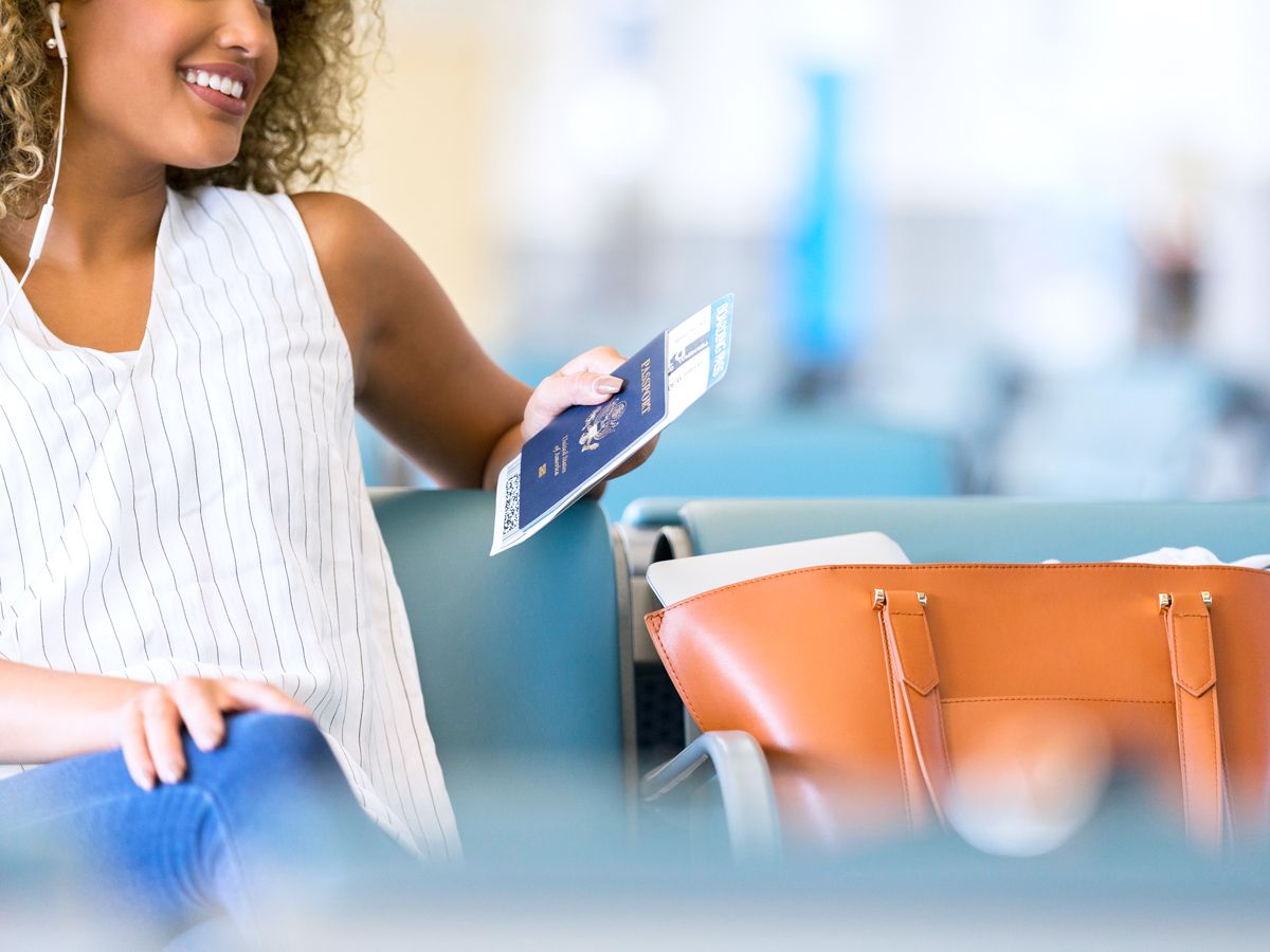 Airline passenger sitting in gate area holding passport