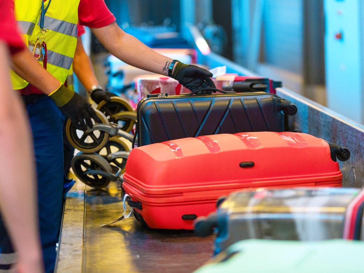 Airport employees handling bags on conveyor belt
