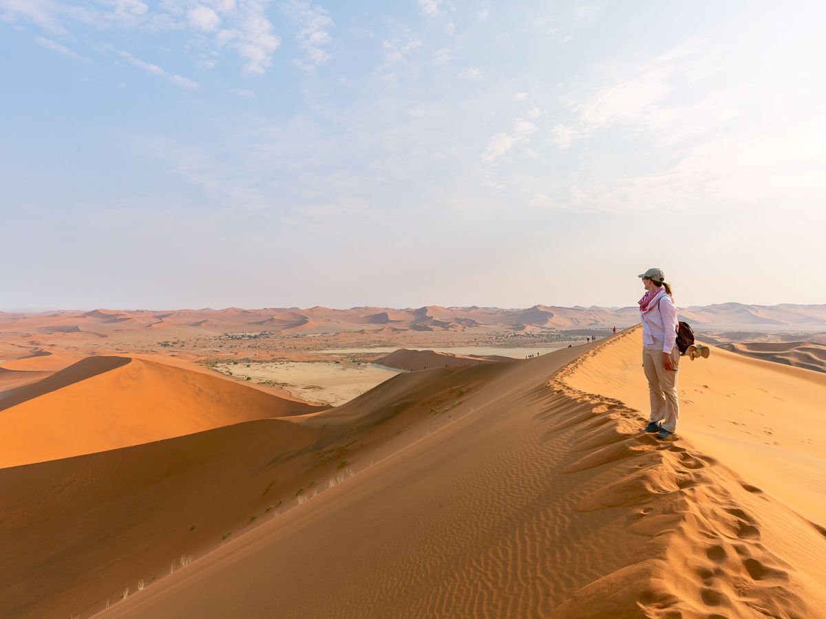 Hiker standing atop sand dune overlooking Death Valley