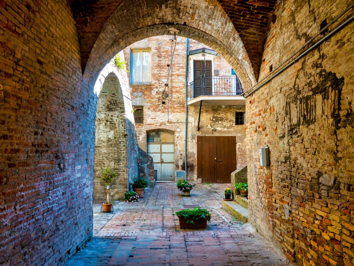 Stone archway and courtyard in village of Penne, Italy