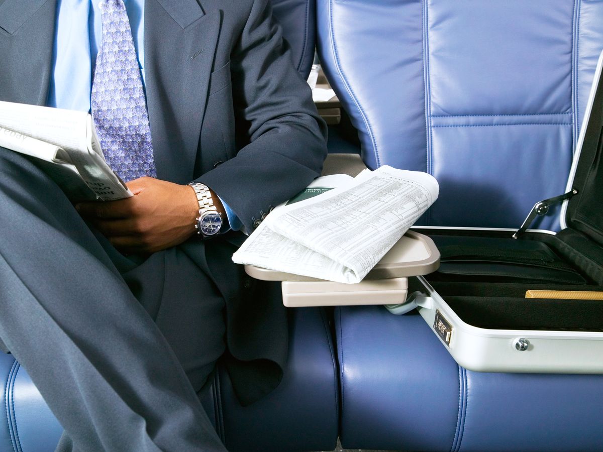 Airplane passenger in suit with items on adjacent seat