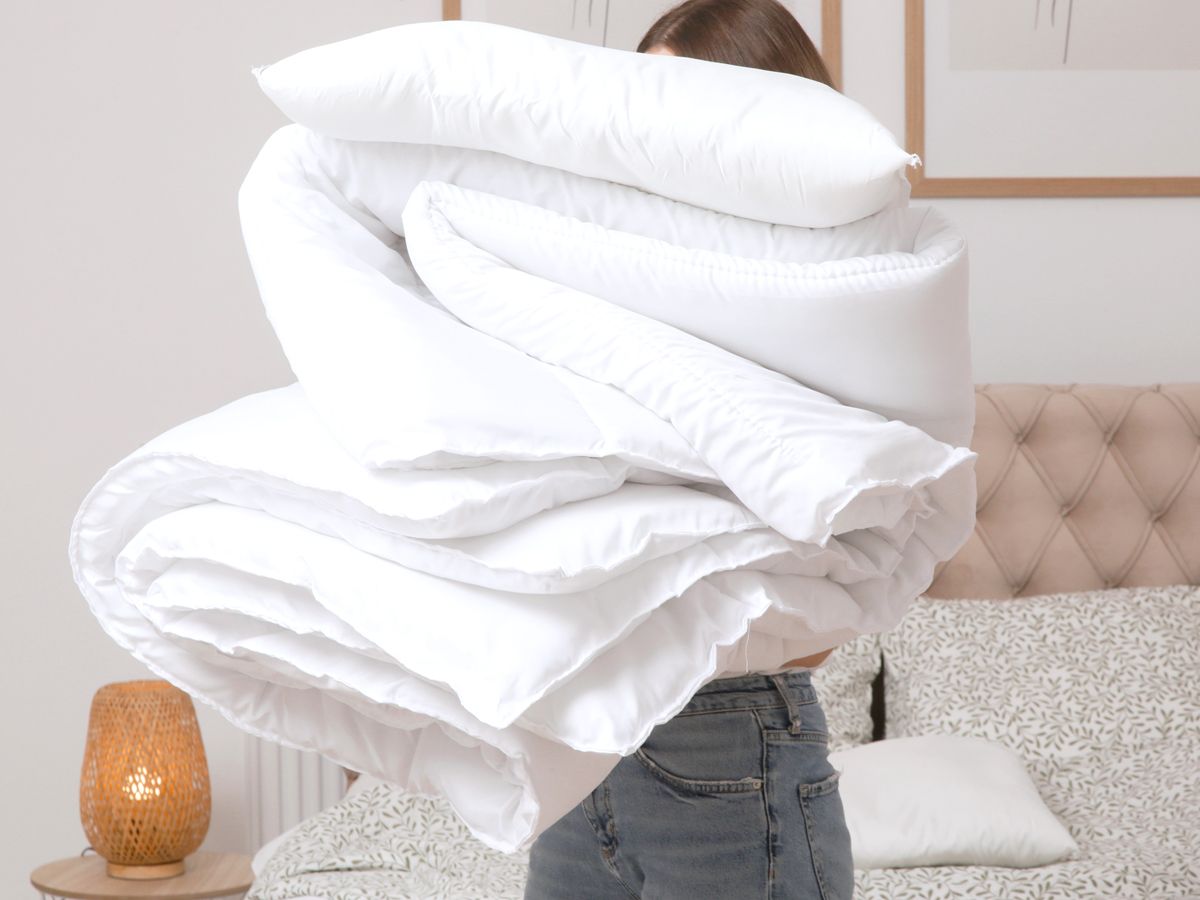 Person carrying pillows and comforter