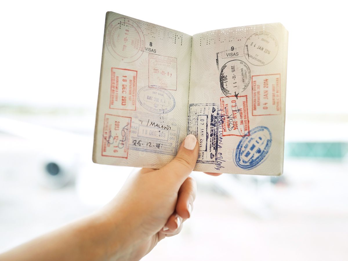 Person holding passport book filled with stamps