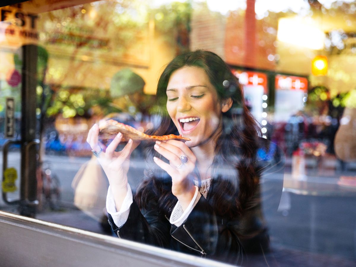 Woman enjoying slice of New York-style pizza