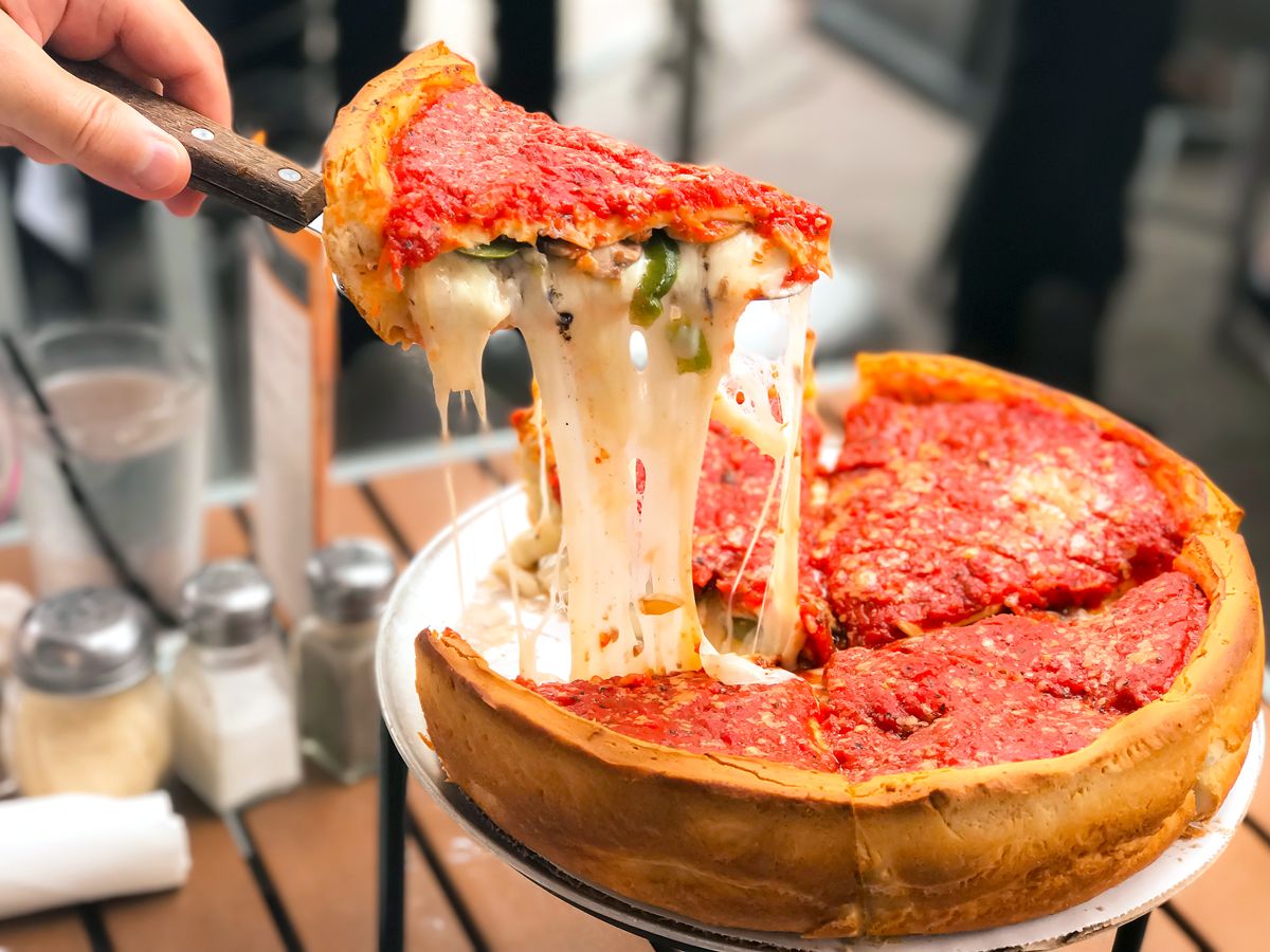 Person serving slice of Chicago deep dish pizza