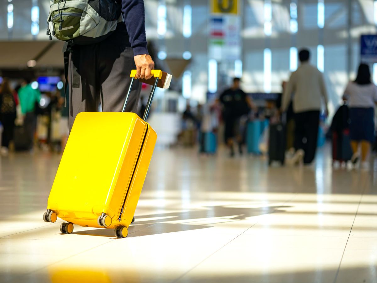 Traveler rolling bright yellow suitcase through airport