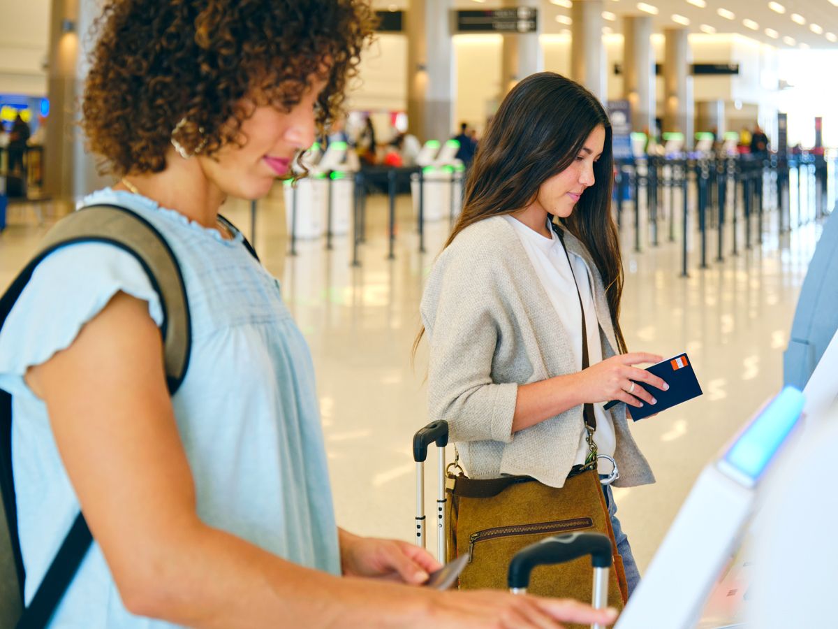 Travelers using electronic kiosk at airport check-in counter