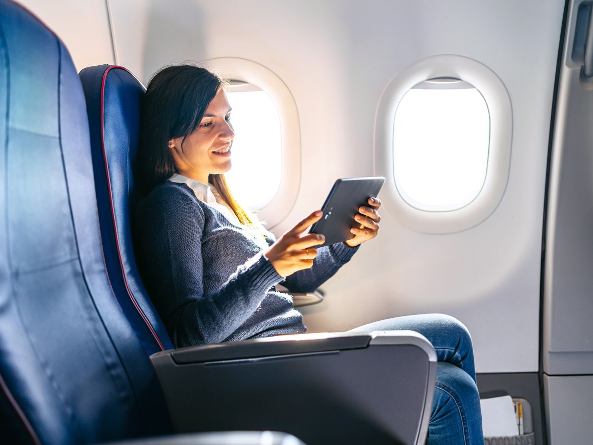 Passenger reading tablet in airplane seat