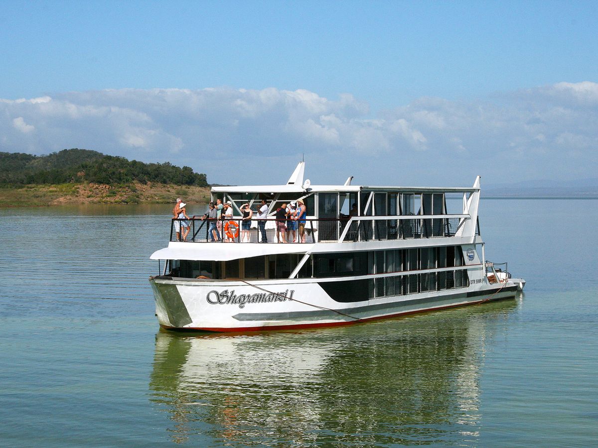 People standing on houseboat deck while it cruises on lake in South Africa