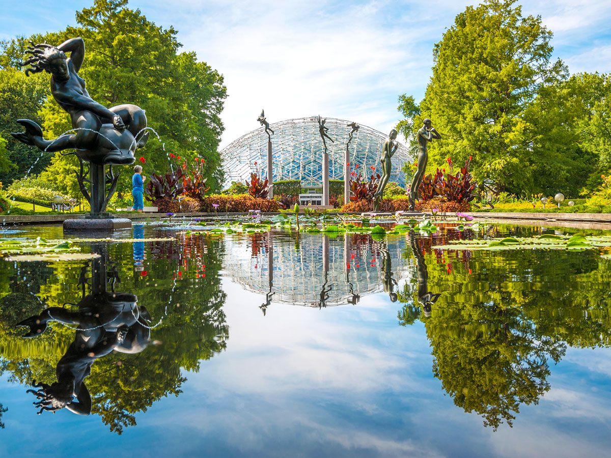 Sculptures and flowers surrounding lake with view of the Climatron at Missouri Botanic Garden
