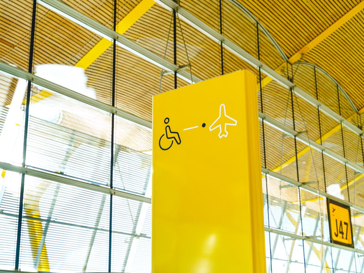 Yellow sign at airport with wheelchair and airplane symbols