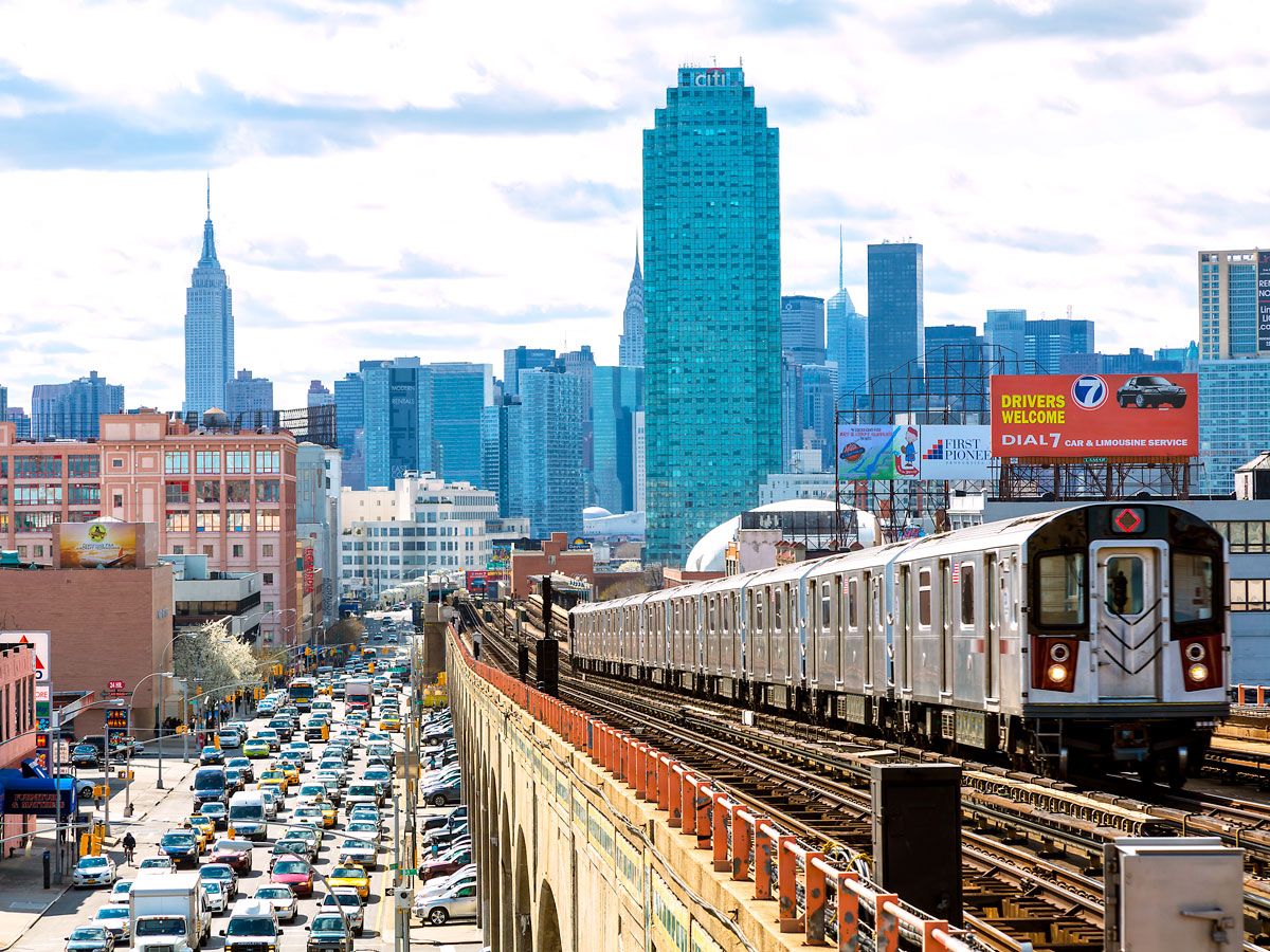 New York City subway train on elevated tracks with view of midtown Manhattan skyline