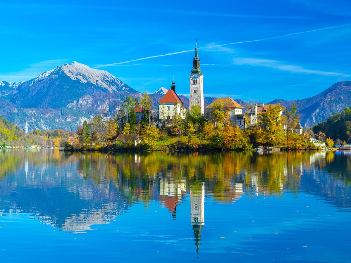 Church on small island in Lake Bled, Slovenia, with reflection on water's surface