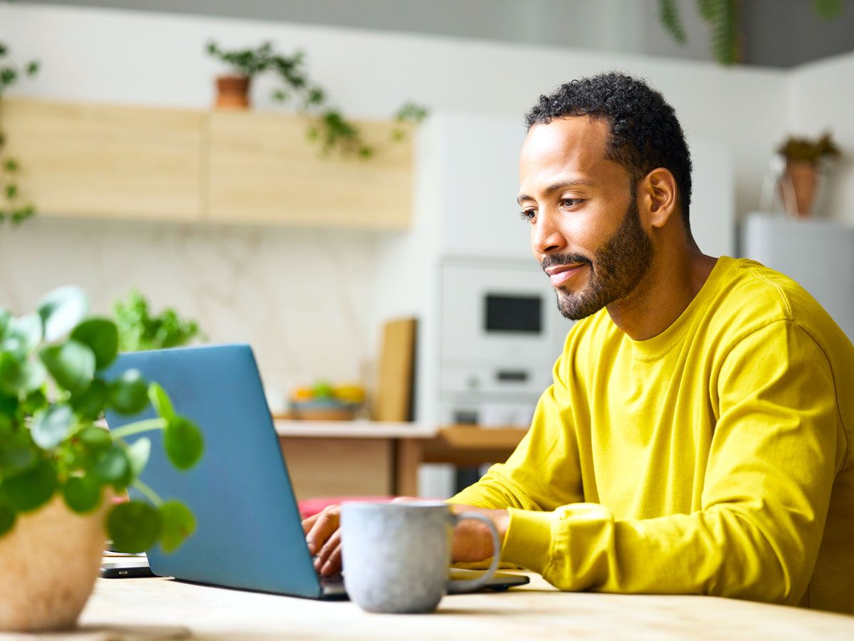 Man sitting at table typing on laptop computer