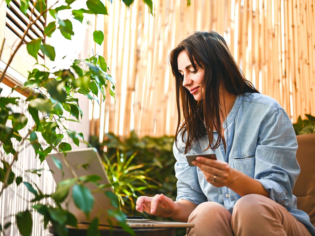 Woman holding credit card and typing on laptop