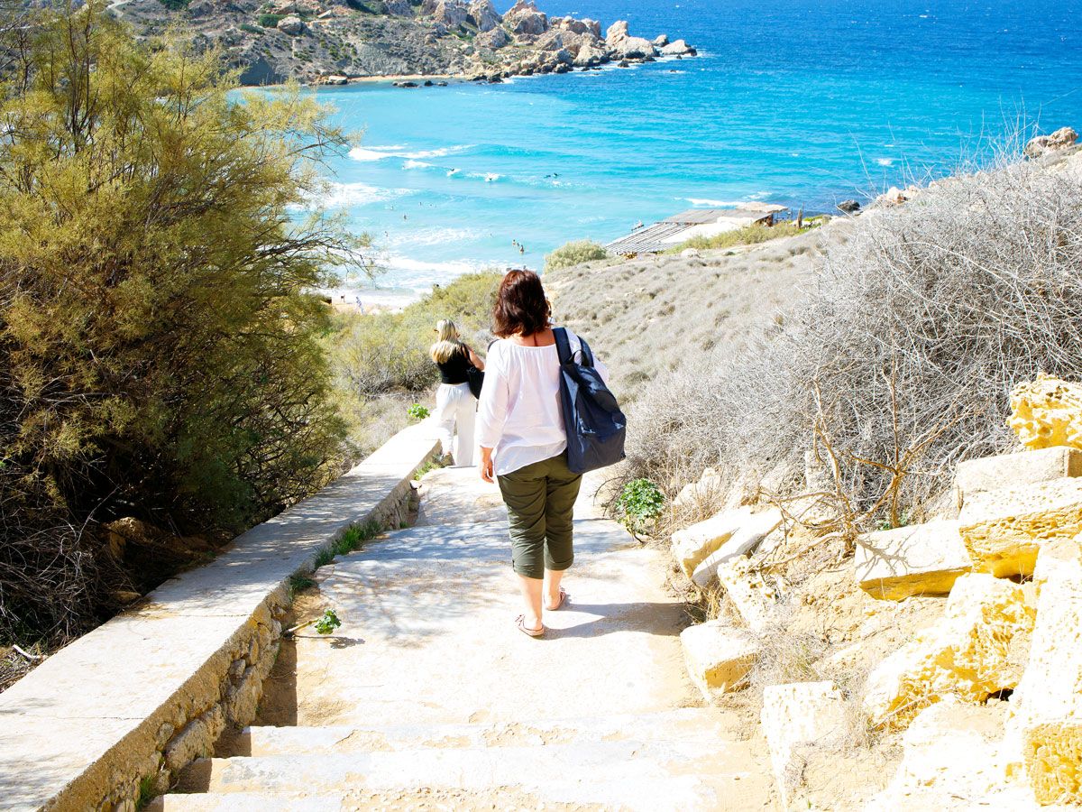 Tourist walking down stairs to beach in Malta
