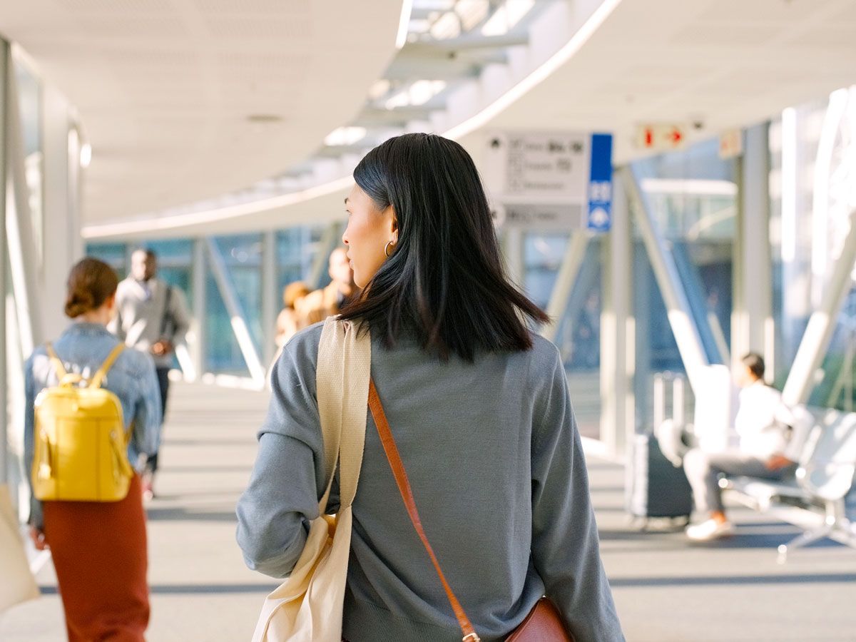 Traveler with shoulder bag walking through airport terminal