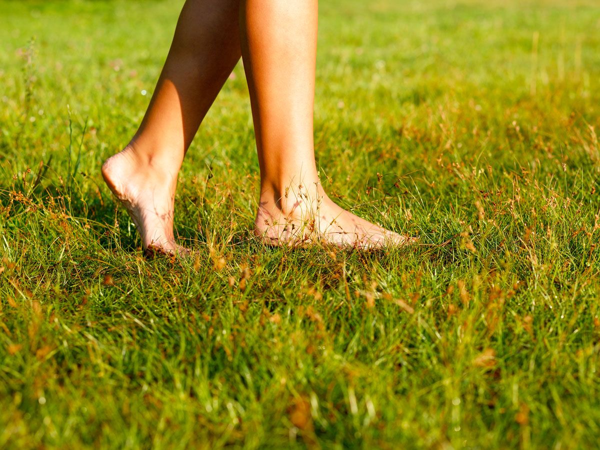 Person walking barefoot in grass