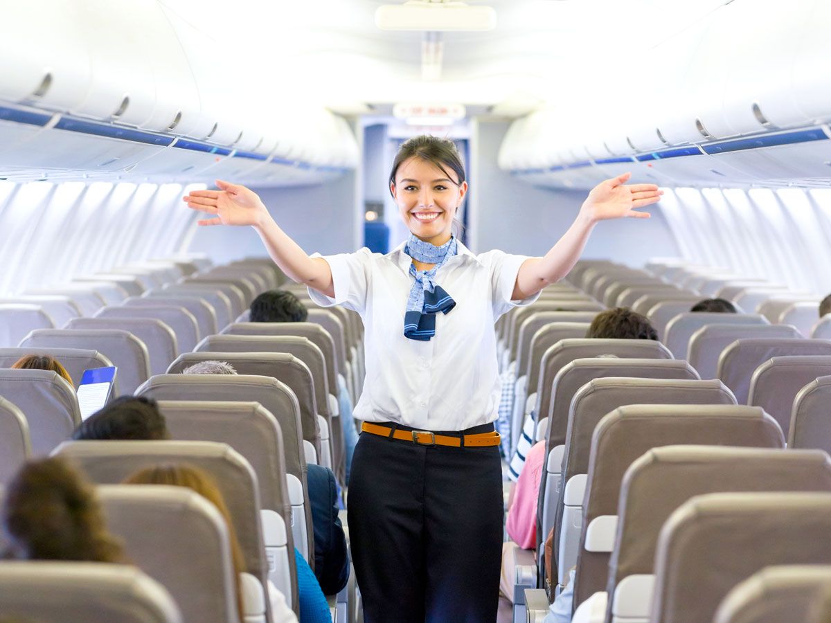 Flight attendant performing safety demonstration in aircraft aisle