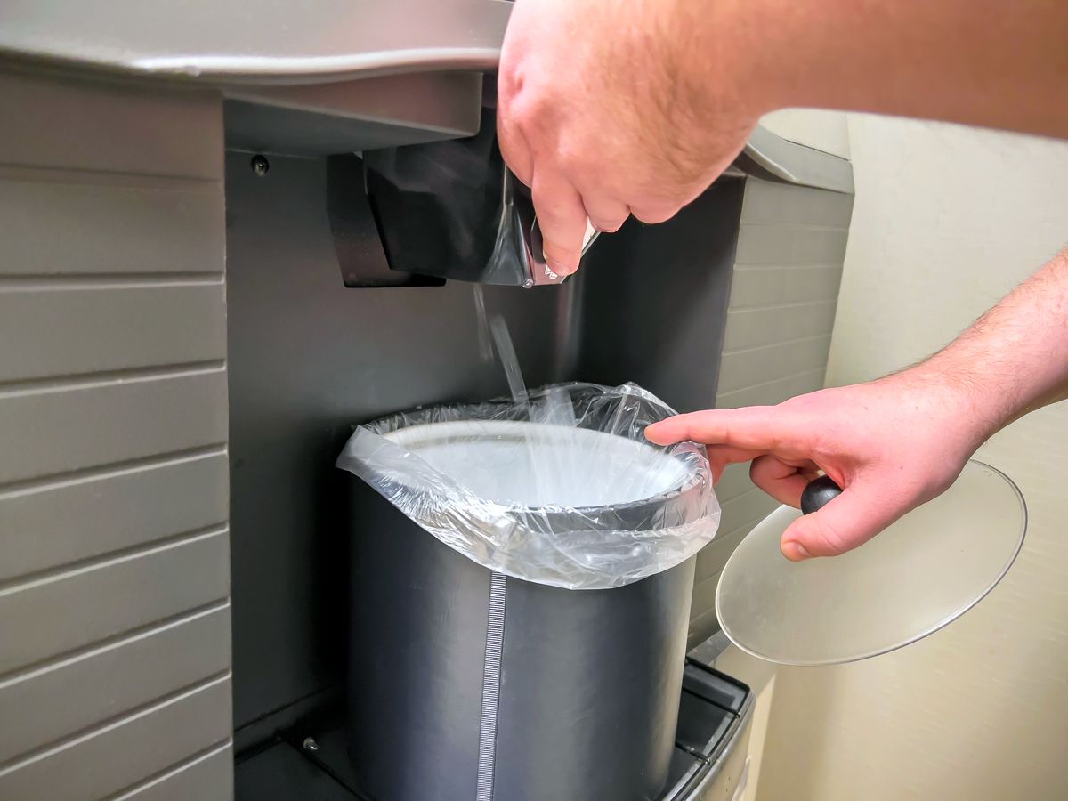 Person filling ice bucket at ice machine in hotel