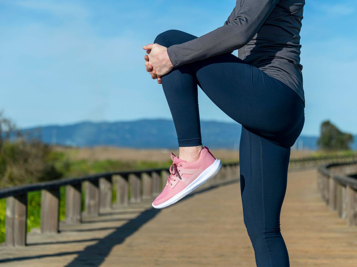 Person lifting knee to chest on walking path