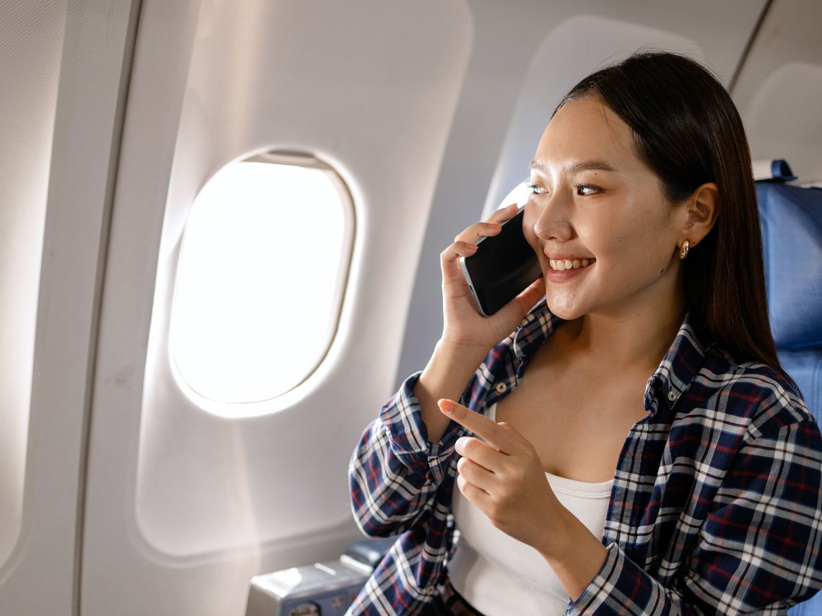 Person talking on cellphone while looking out airplane window