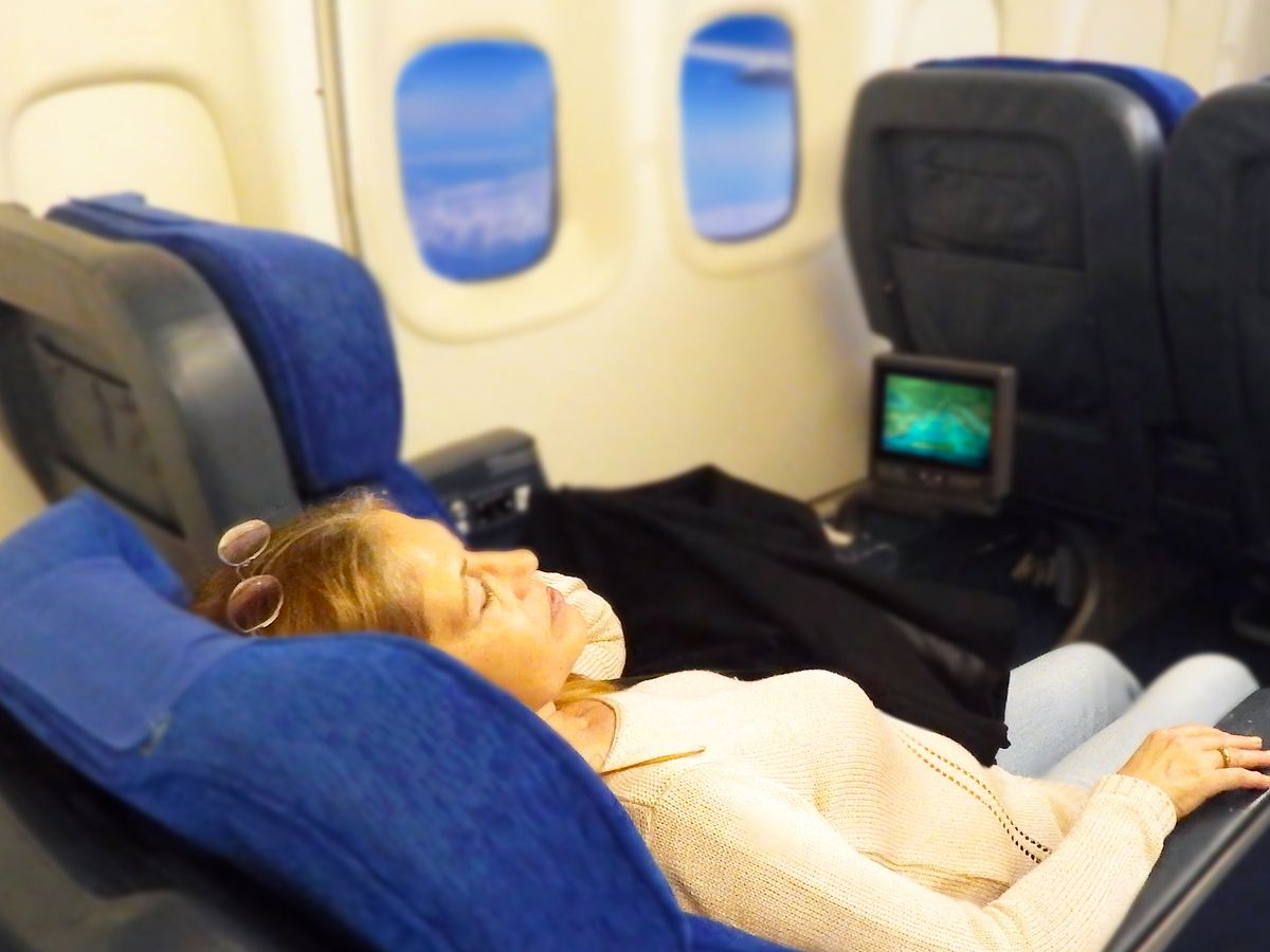 Passenger sleeping in reclined airplane seat