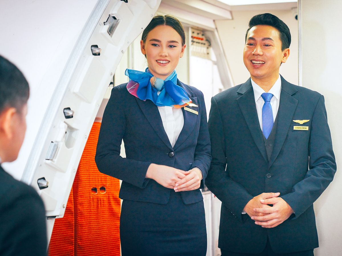 Flight attendants greeting passengers at boarding door