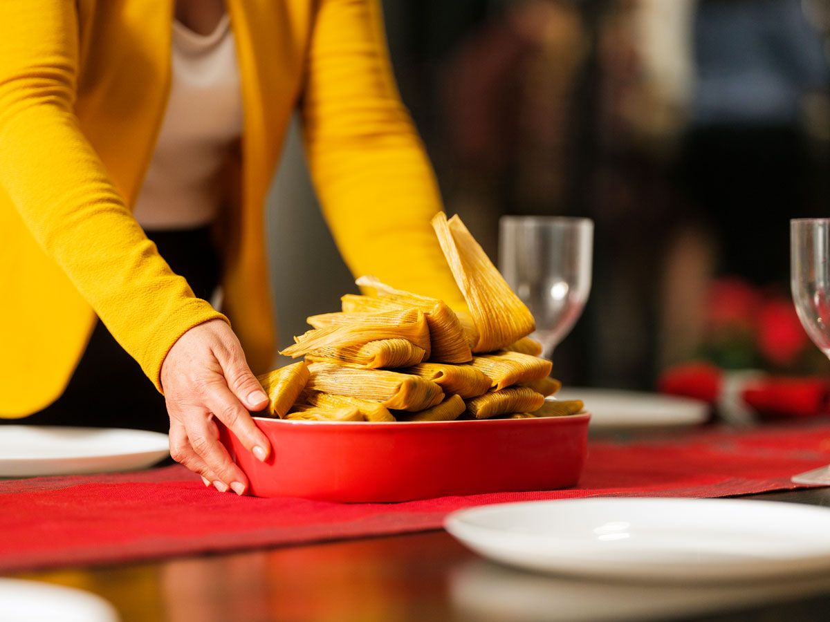 Person placing bowl of tamales on table