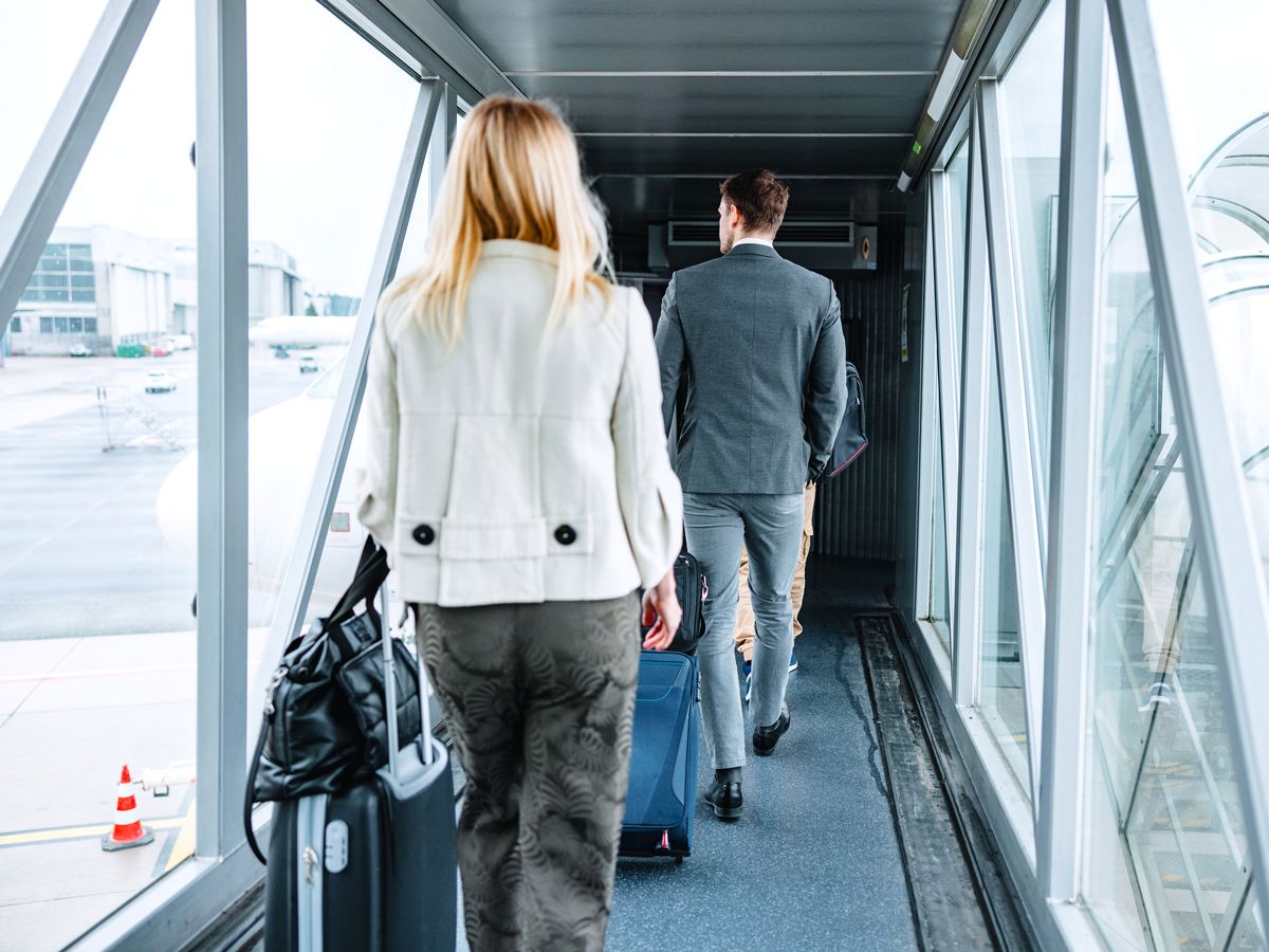 Passengers inside glass jet bridge waiting to board aircraft 
