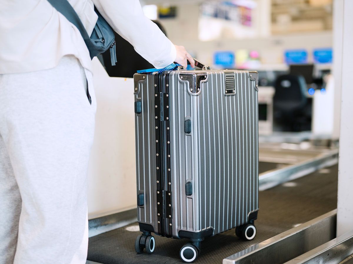Traveler placing hard-sided luggage on check-in belt