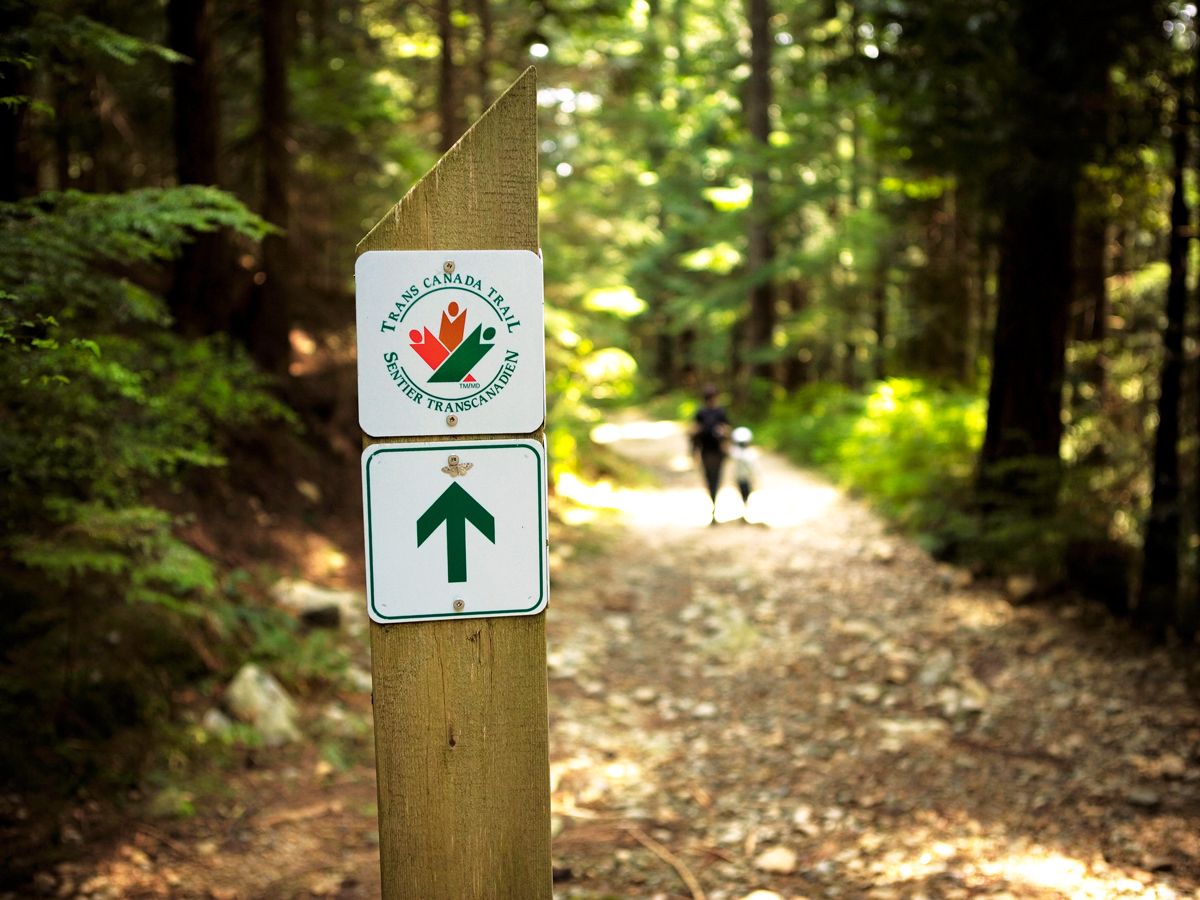 Trail marker and hikers on the Trans Canada Trail