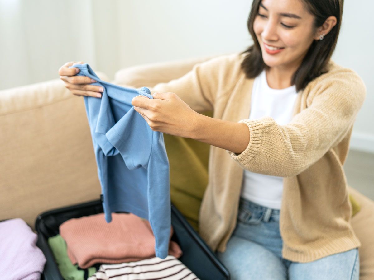 Woman sitting on couch packing suitcase