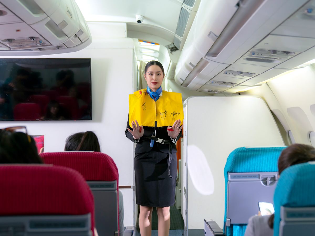 Flight attendant performing safety demonstration in aircraft aisle