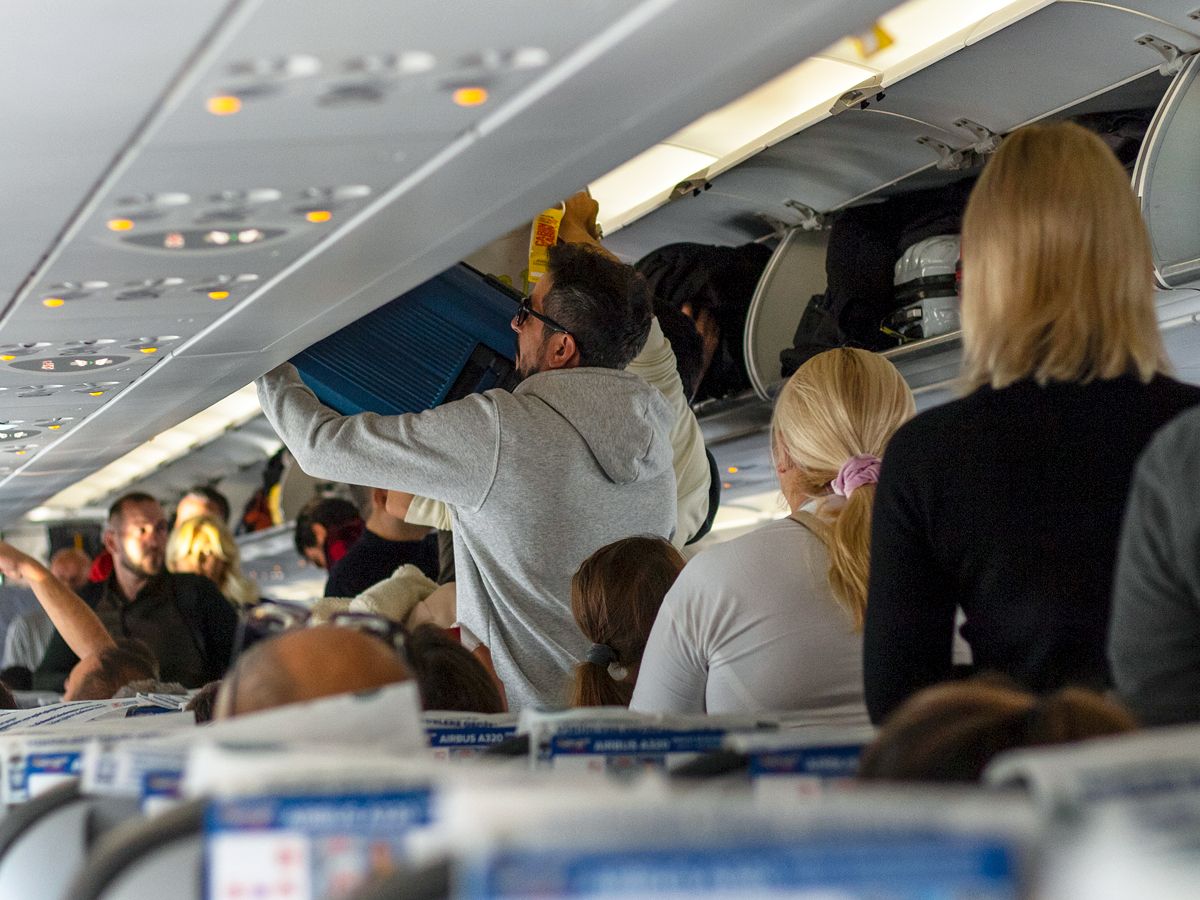 Passengers stowing bags as they board a plane