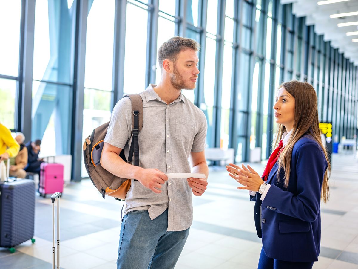 Passenger speaking to airline employee in terminal