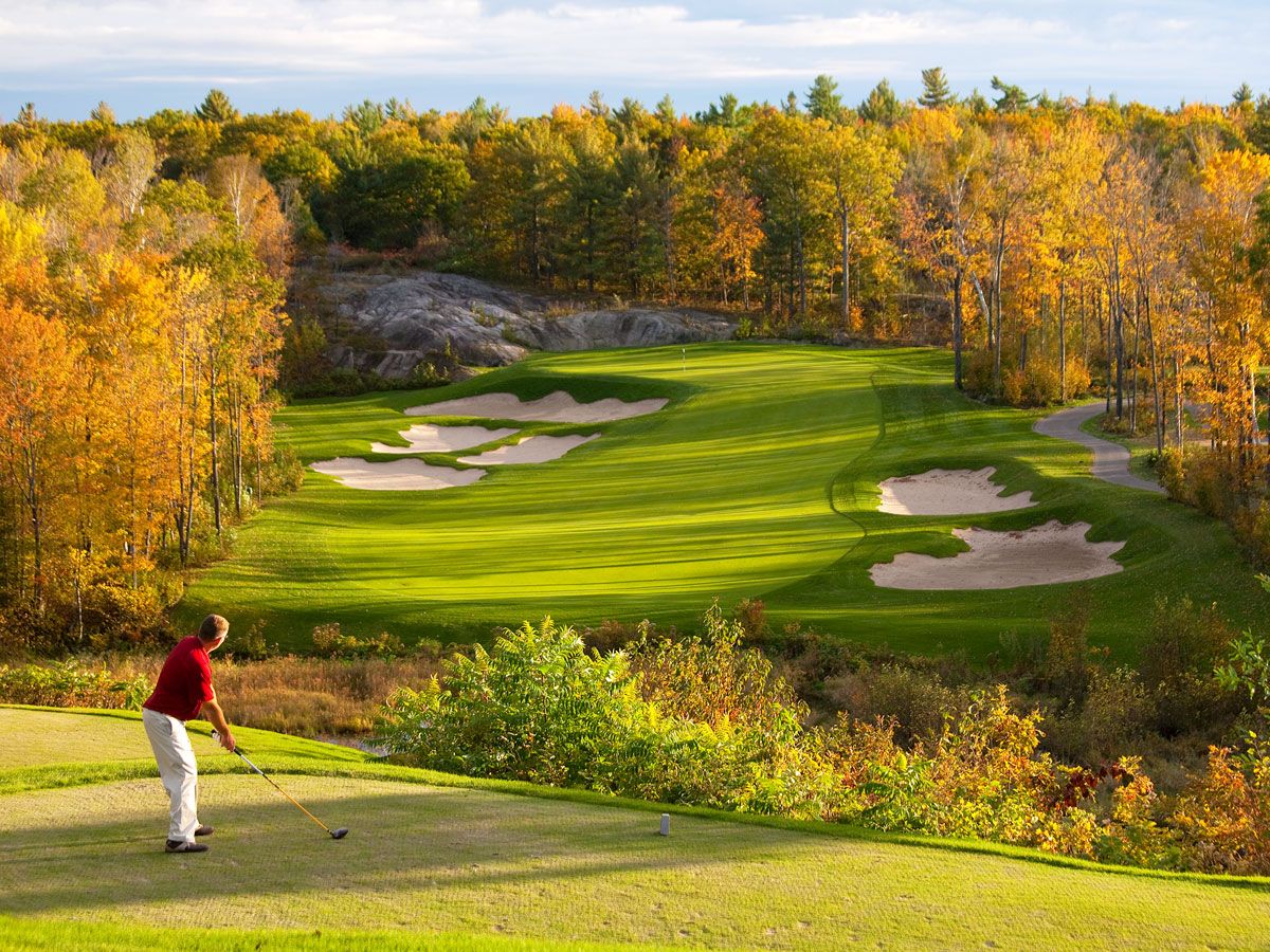 Person golfing at course surrounded by fall foliage