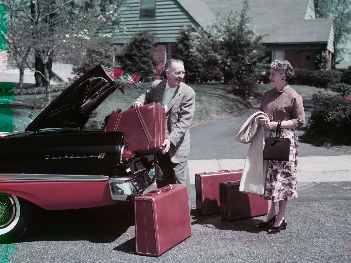 Man and woman packing trunks into car in 1950s