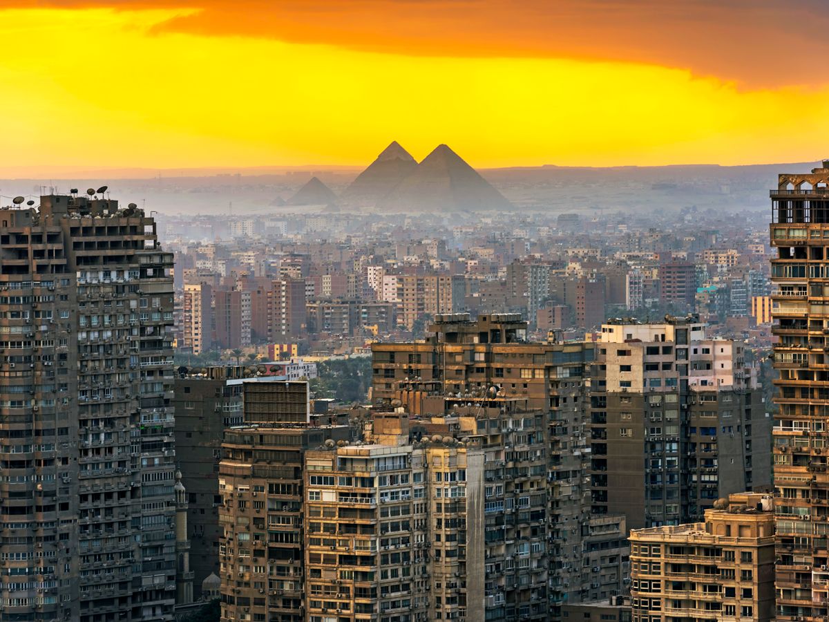 Pyramids of Giza seen beyond Cairo skyline at sunset